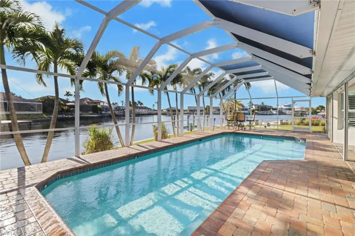 View of swimming pool featuring a dock, a water view, glass enclosure, and a patio area