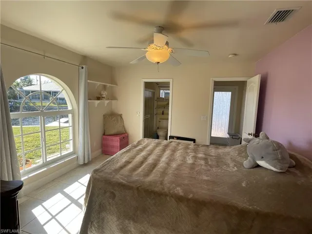 Tiled bedroom featuring ensuite bath and ceiling fan