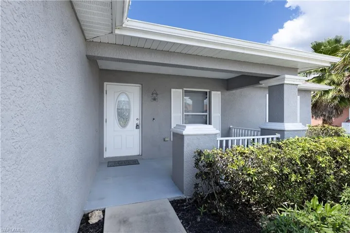 Property entrance with covered porch and stucco siding