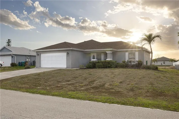 Ranch-style house with stucco siding, driveway, a yard, and a garage