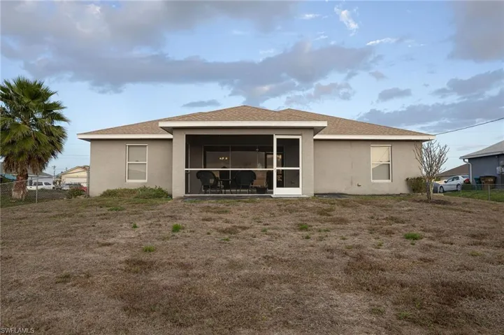 Back of house featuring stucco siding, roof with shingles, and a sunroom