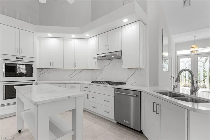 Kitchen featuring stainless steel appliances, under cabinet range hood, backsplash, white cabinetry, and recessed lighting