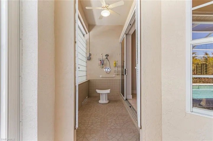 Bathroom featuring a textured wall, a ceiling fan, tile patterned flooring, and an enclosed shower