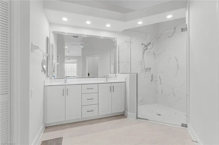 Full bath with recessed lighting, double vanity, a marble finish shower, a ceiling fan, and tile patterned floors