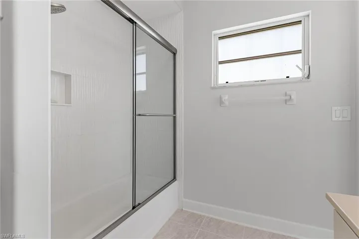 Full bathroom featuring shower / bath combination with glass door, vanity, and tile patterned flooring