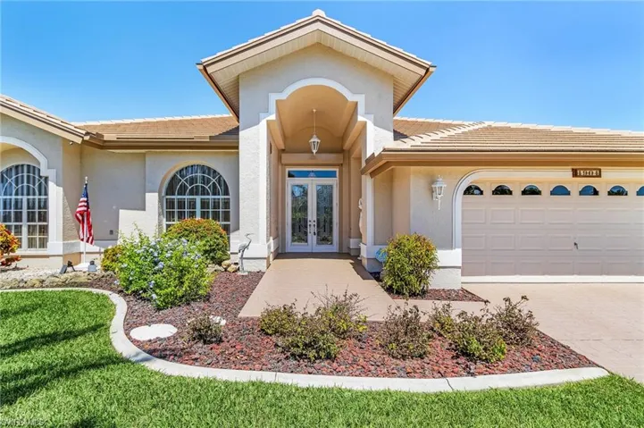 Property entrance featuring french doors, a tiled roof, stucco siding, and an attached garage