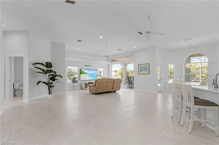 Living area with ceiling fan, light tile patterned floors, a towering ceiling, and recessed lighting