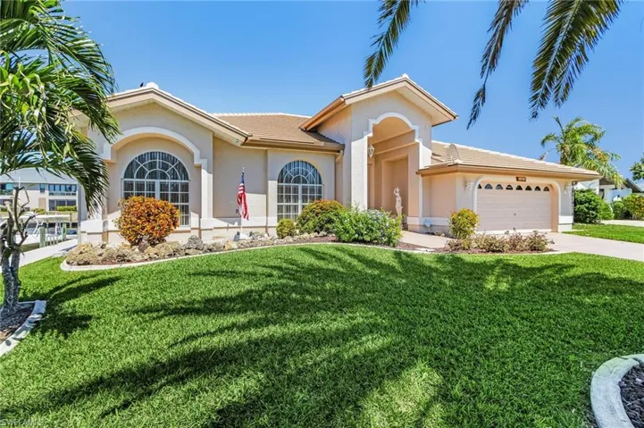 Ranch-style house featuring stucco siding, an attached garage, a front yard, and driveway