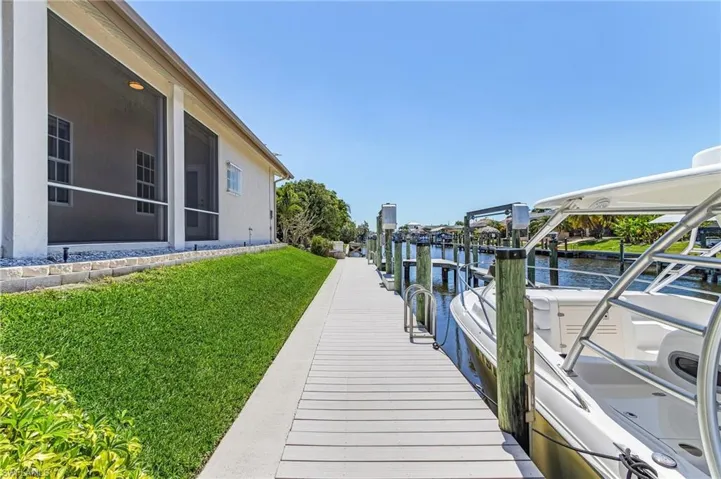 Dock area with a water view, a lawn, and boat lift