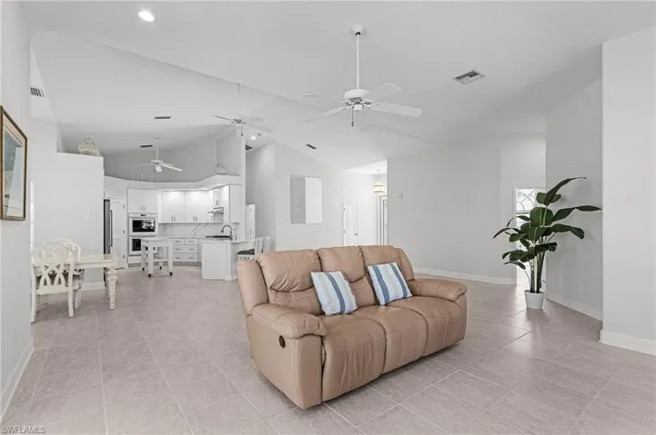 Living area with ceiling fan, light tile patterned floors, high vaulted ceiling, and recessed lighting
