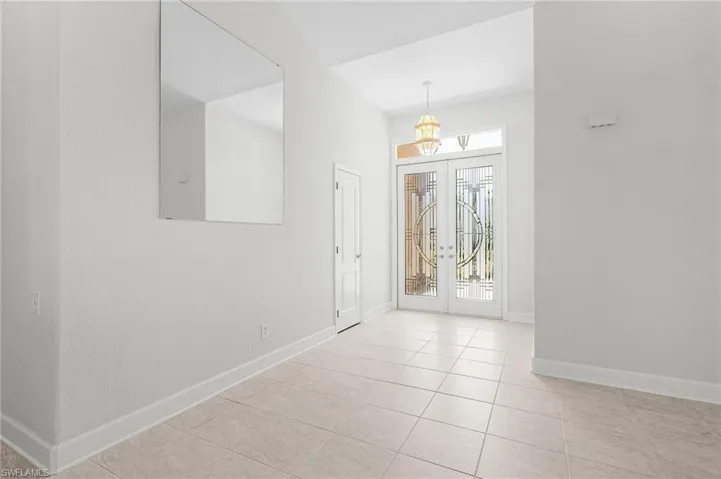 Tiled foyer featuring french doors and a chandelier