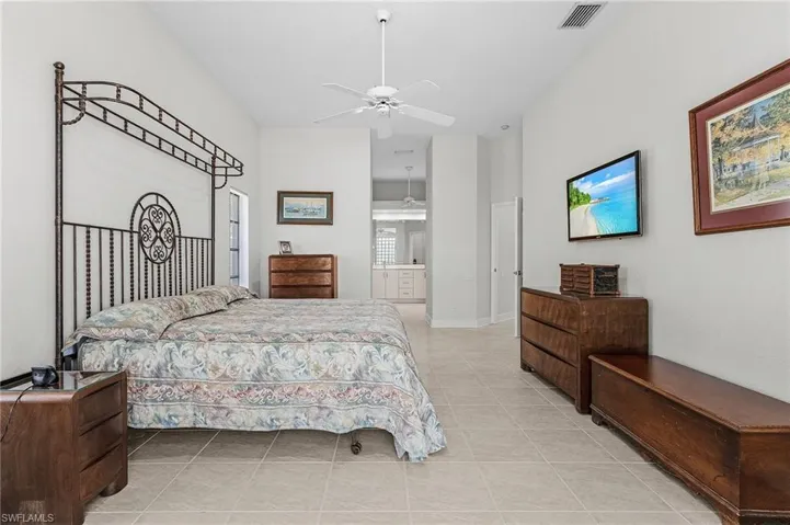 Bedroom featuring light tile patterned floors, a towering ceiling, ceiling fan, and ensuite bathroom
