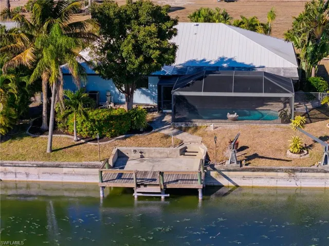 Rear view of house with a lanai, a water view, a sunroom, and an outdoor pool