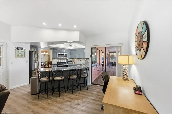 Kitchen featuring a kitchen bar, stainless steel appliances, light wood-style flooring, a peninsula, and dark stone counters