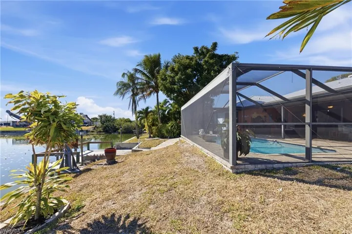 View of green lawn with a lanai, an outdoor pool, a sunroom, a water view, and a patio