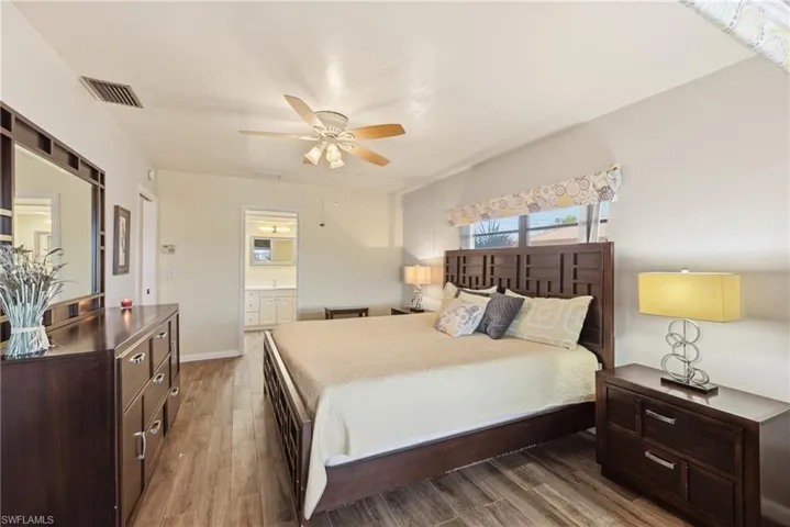 Bedroom featuring light wood-style flooring, ensuite bathroom, and ceiling fan