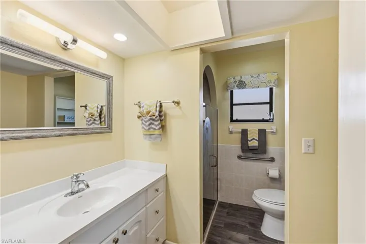 Bathroom with vanity, a shower stall, tile walls, and dark wood-style floors