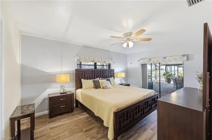 Bedroom with access to exterior, wood finished floors, multiple windows, and a ceiling fan