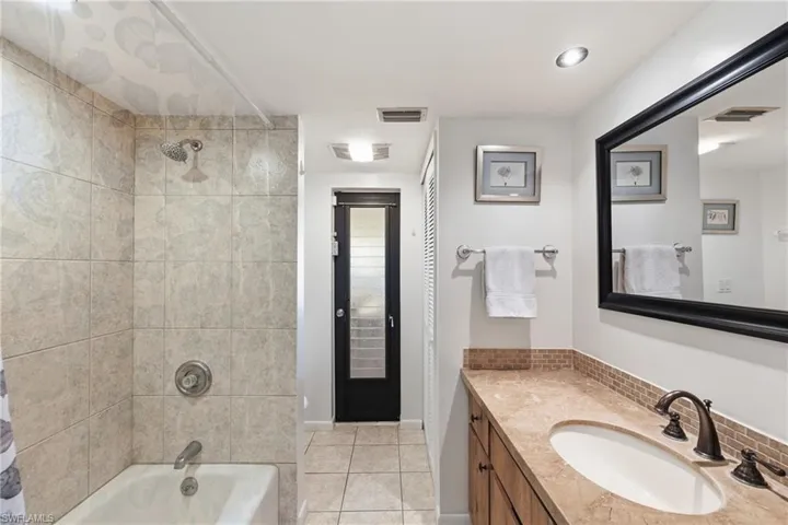 Full bath featuring vanity, shower / bathtub combination with curtain, and light tile patterned flooring