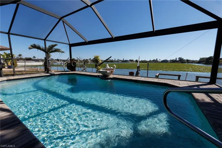Outdoor pool featuring glass enclosure, a water view, and a sunroom