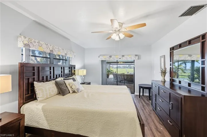 Bedroom with multiple windows, access to outside, dark wood-style flooring, and a ceiling fan