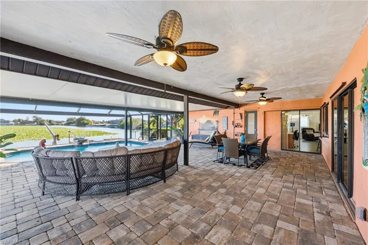 View of patio featuring outdoor dining area, a sunroom, an outdoor pool, and ceiling fan