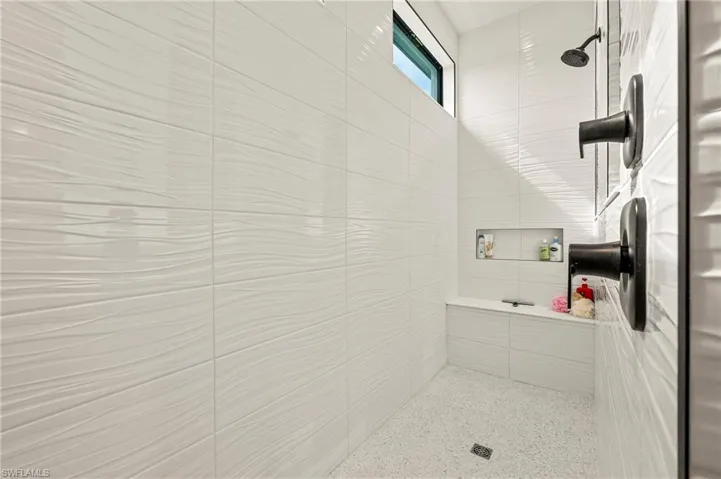 Primary bathroom walk-in shower with multiple facet heads and bench seating