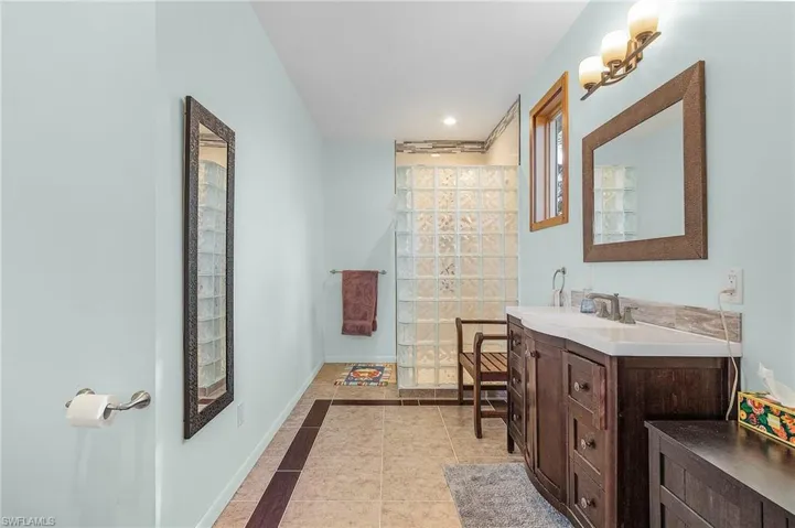 Owner's Bathroom featuring a glass block shower, custom vanity, and tile patterned flooring