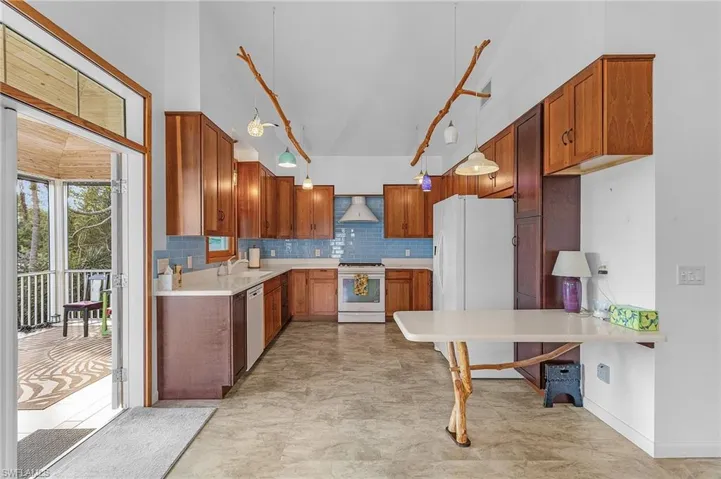 Kitchen featuring custom cabinets, gas stove, high vaulted ceiling, backsplash, and unique pendant lighting
