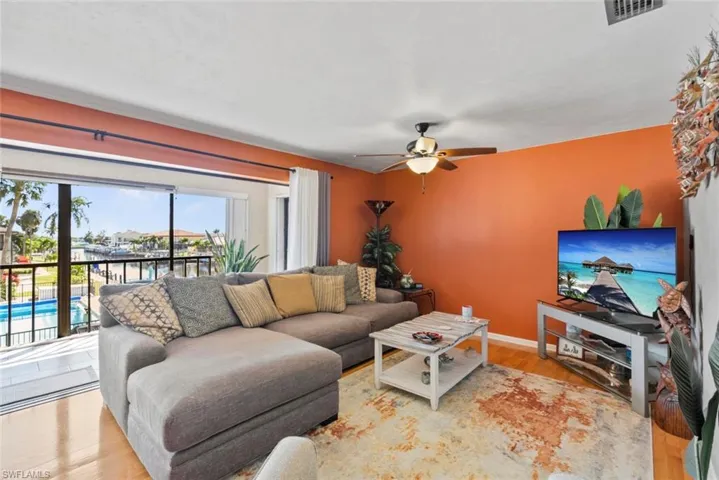 Living area featuring a ceiling fan, baseboards, visible vents, and wood finished floors