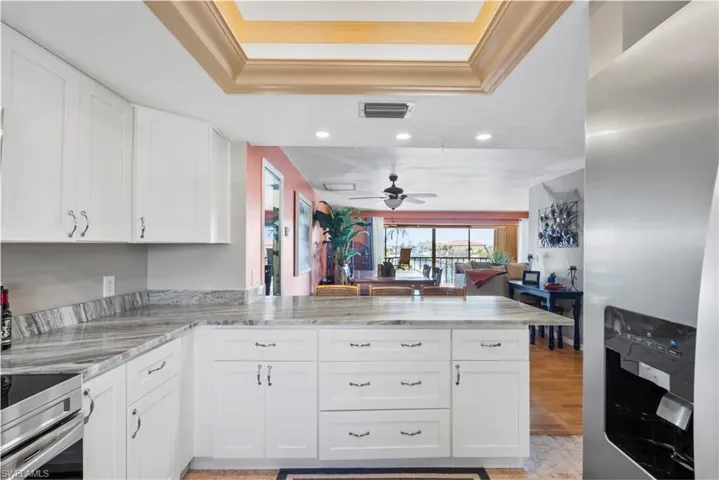 Kitchen featuring a raised ceiling, visible vents, range, and a peninsula