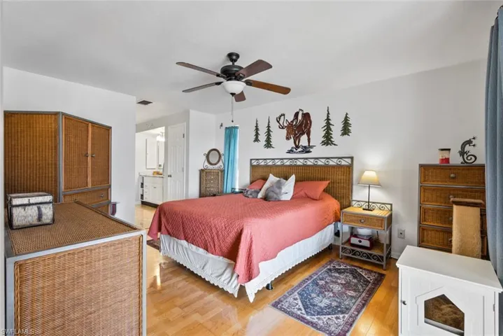 Bedroom featuring visible vents, ceiling fan, ensuite bath, and wood finished floors