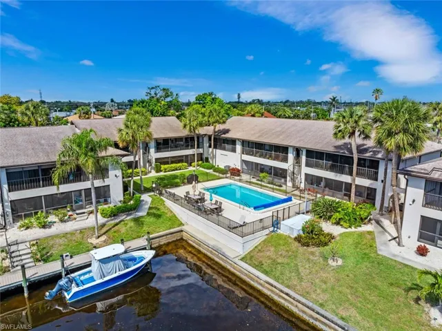 Back of condo, water and dock view, fence, and a community pool