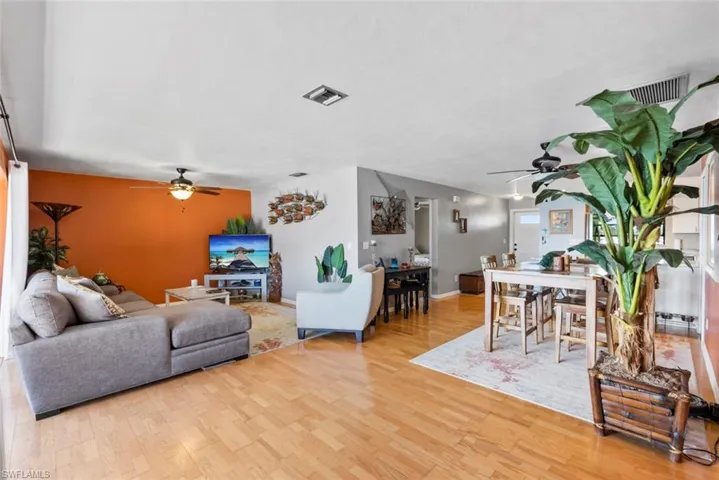 Living area with ceiling fan, light wood finished floors, and visible vents