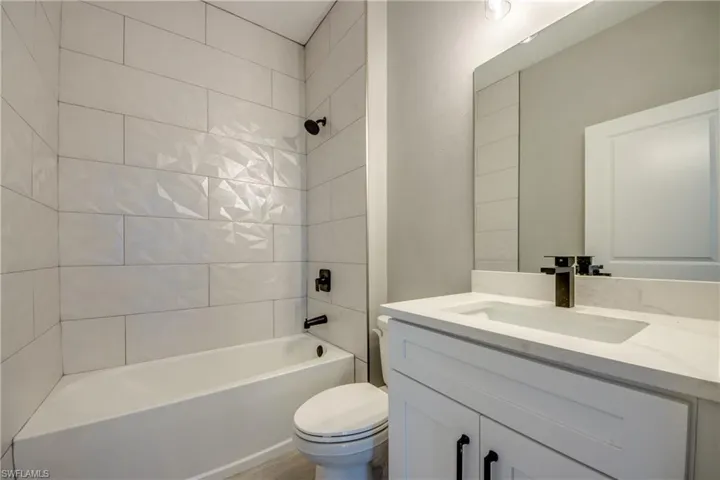 Full bathroom featuring toilet, large vanity, and tiled shower / bath