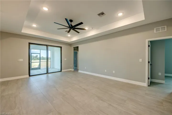 Tiled empty room featuring ceiling fan and a raised ceiling