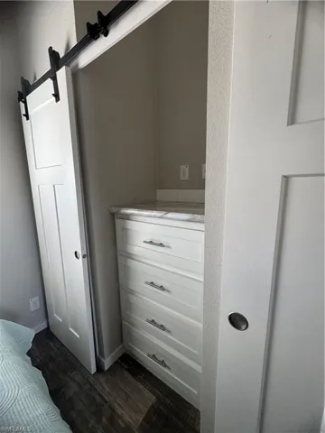 Detailed view of a barn door, wood finished floors, and a textured wall