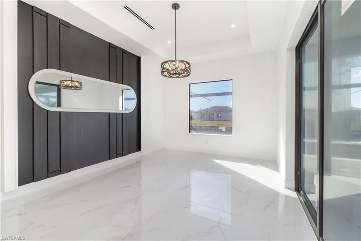 Unfurnished room with a notable chandelier and a tray ceiling