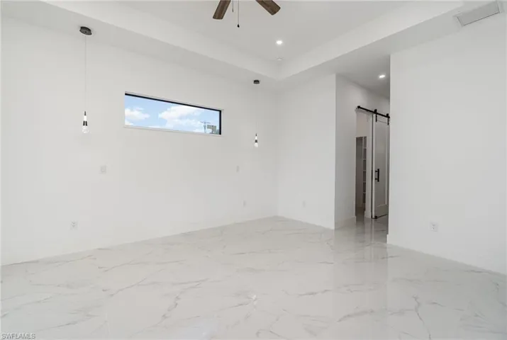 Empty room featuring ceiling fan and a barn door