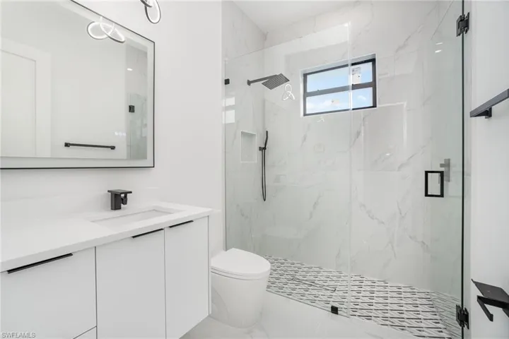 Bathroom with toilet, walk in shower, and vanity