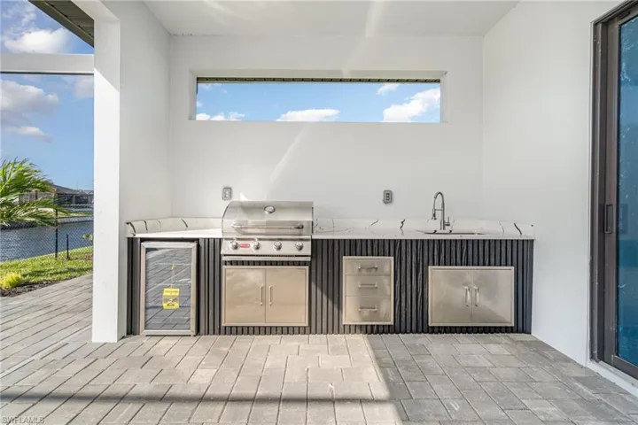 View of patio with area for grilling, sink, and a water view