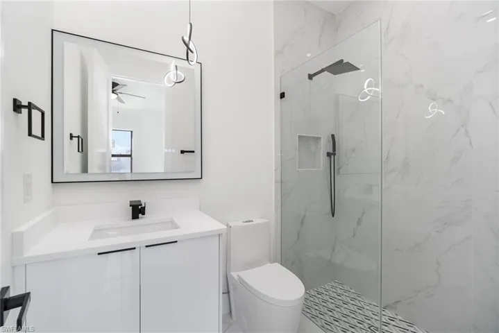 Bathroom with vanity, a shower with shower door, and toilet