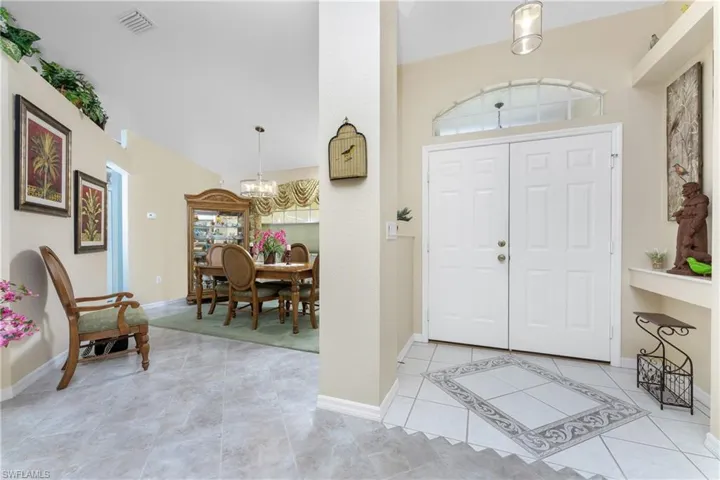 Tiled foyer with a healthy amount of sunlight, an inviting chandelier, and high vaulted ceiling