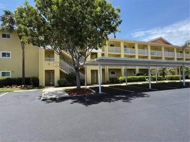 View of building exterior with covered parking and stairs
