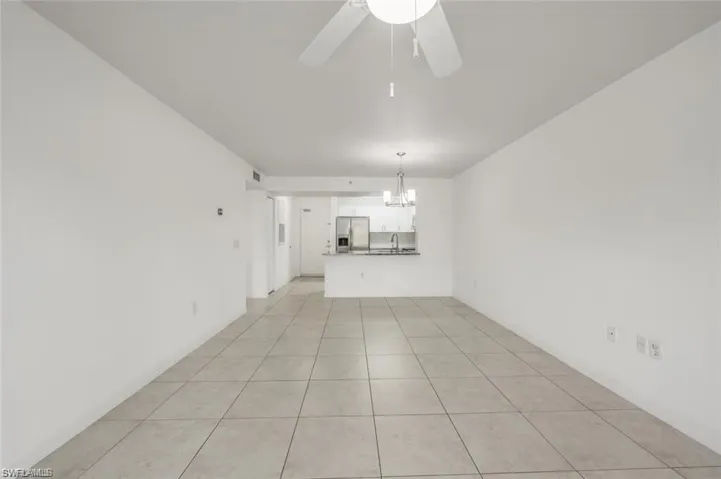 Unfurnished living room featuring light tile patterned flooring, a ceiling fan, and a chandelier