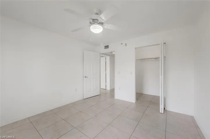 Unfurnished bedroom featuring a ceiling fan, light tile patterned floors, and a closet