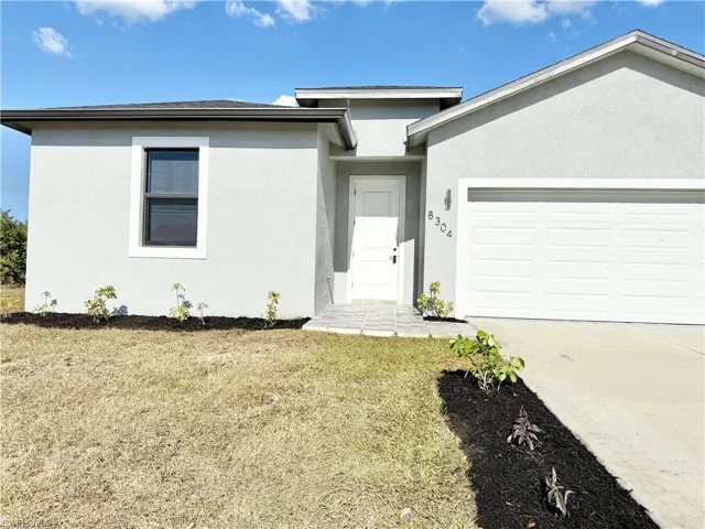 View of front of home featuring a front lawn, stucco siding, an attached garage, and driveway