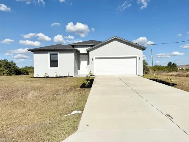 Ranch-style house with stucco siding, a garage, driveway, and a front yard