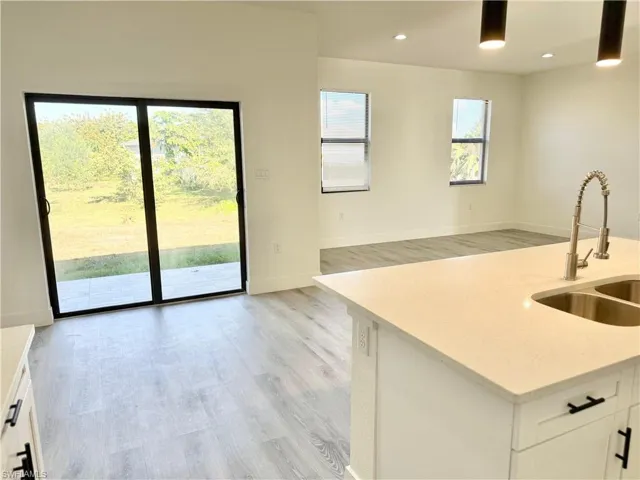 Kitchen with light stone countertops, white cabinets, light wood-style flooring, and recessed lighting