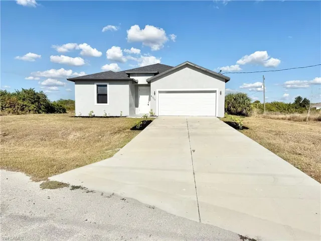 Single story home featuring stucco siding, concrete driveway, a front lawn, and an attached garage